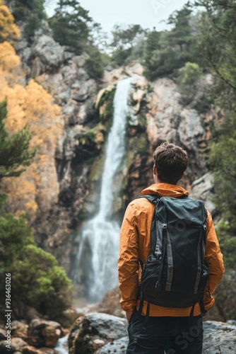 Hiker at a majestic waterfall in the mountains on a cloudy day