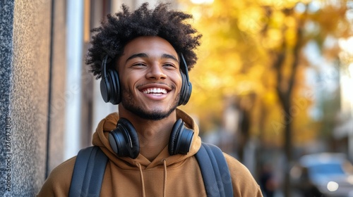 Young man enjoying autumn outdoors while listening to music with headphones