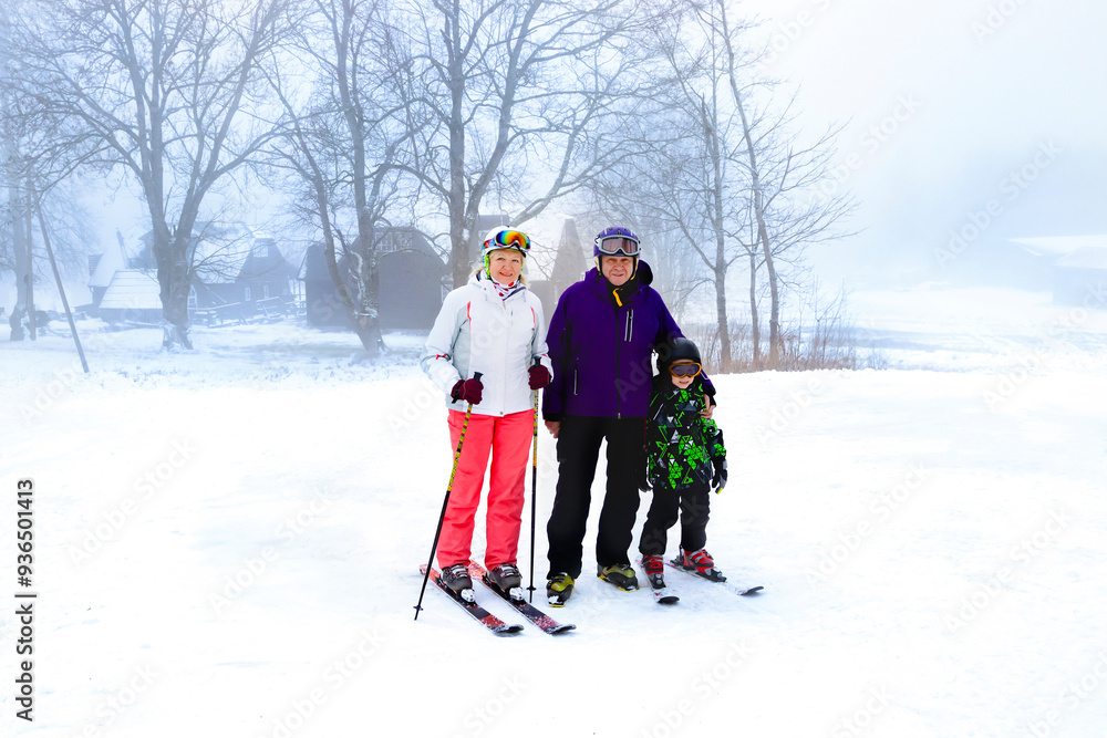 A joyful family filled with happiness enjoys skiing together in a beautiful snowy landscape surrounded by fog and trees