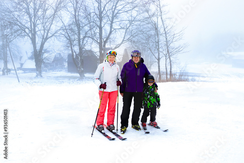 Obraz na płótnie A joyful family filled with happiness enjoys skiing together in a beautiful snowy landscape surrounded by fog and trees w salonie