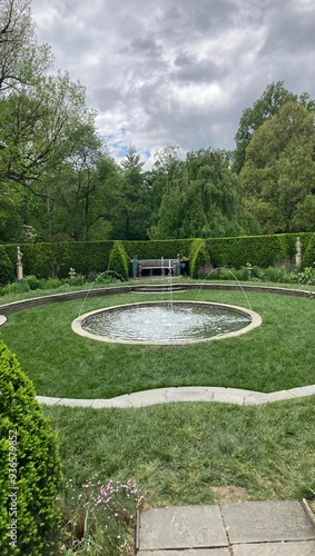 Fountain implanted in garden with surrounding hedges