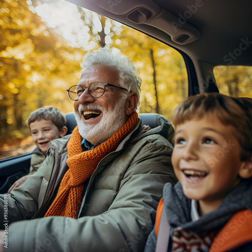 elderly man around 70 years old, with grey hair, drives a car. In the backseat, two young children. The car travels down a road lined with autumn trees