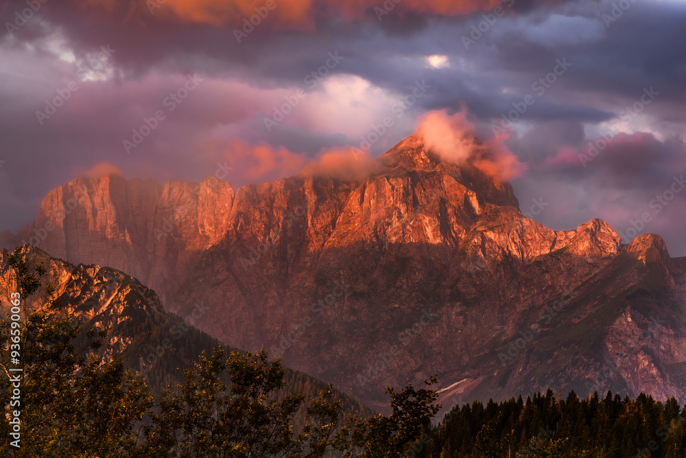 Fototapeta premium Romantic colorful sunrise in the mountains on the border between Slovenia, Austria and Italy. Breathtaking moment when the sun paint colors across the whole sky and into the clouds.