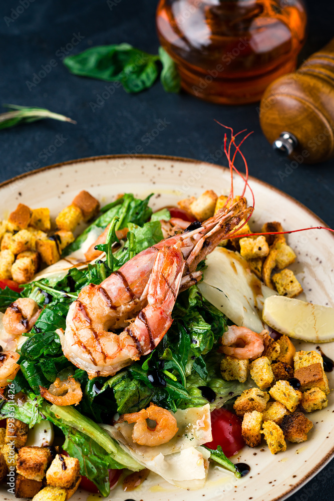 Italian Caesar salad with crawfish, shrimp, parmesan cheese, lettuce, tomatoes, croutons on a dark table. Italian Caesar salad with crawfish, shrimp, parmesan cheese, lettuce, tomatoes, croutons on a dark table.
