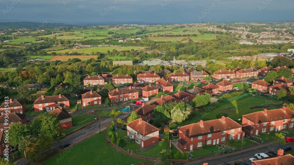 UK housing district: Aerial view of Yorkshire's red brick council estate, lit by the morning sun, featuring homes and people on the streets. UK housing district: Aerial view of Yorkshire's red brick council estate, lit by the morning sun, featuring homes and people on the streets.