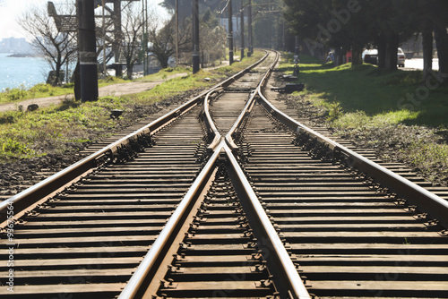 Railway station junctions. 2 Two railway tracks merge together. Rail way track along Black Sea with switch and interchange. empty railroad fork. wooden sleepers. Batumi, Georgia.