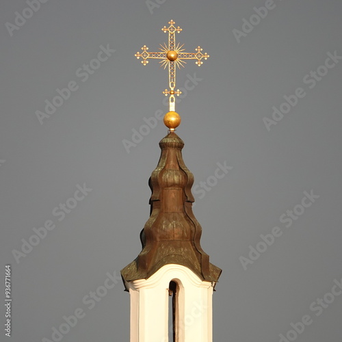 A close-up of the golden cross of the Orthodox Church against the gray sky. Orthodox cross made of gold on the dome of a church in Russia. photo