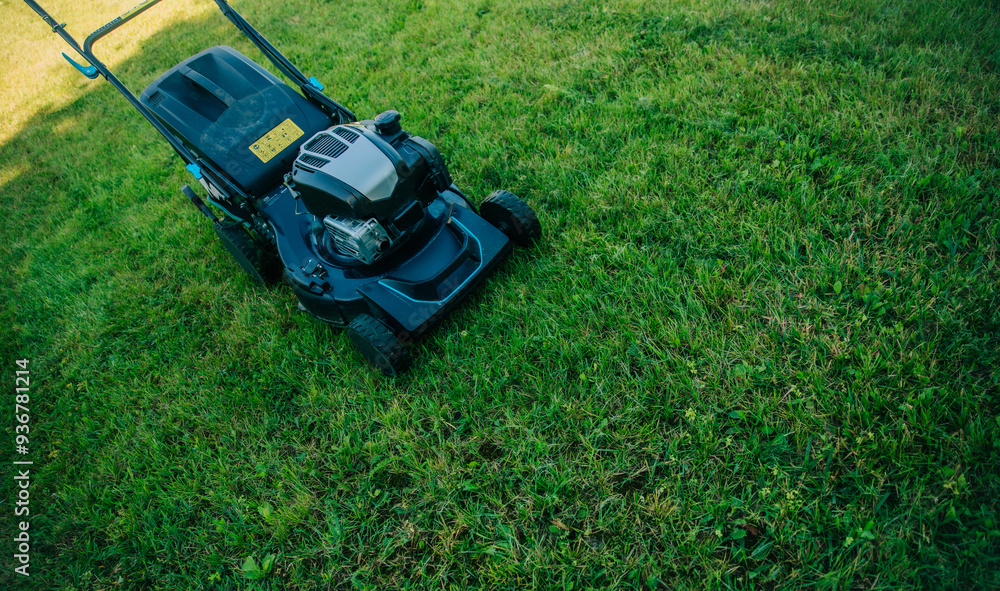 A lawn mower sits on a freshly cut lawn, ready for use in a well-maintained garden. Essence of outdoor maintenance, showcasing the tools essential for keeping a lawn in perfect condition. A lawn mower sits on a freshly cut lawn, ready for use in a well-maintained garden. Essence of outdoor maintenance, showcasing the tools essential for keeping a lawn in perfect condition.