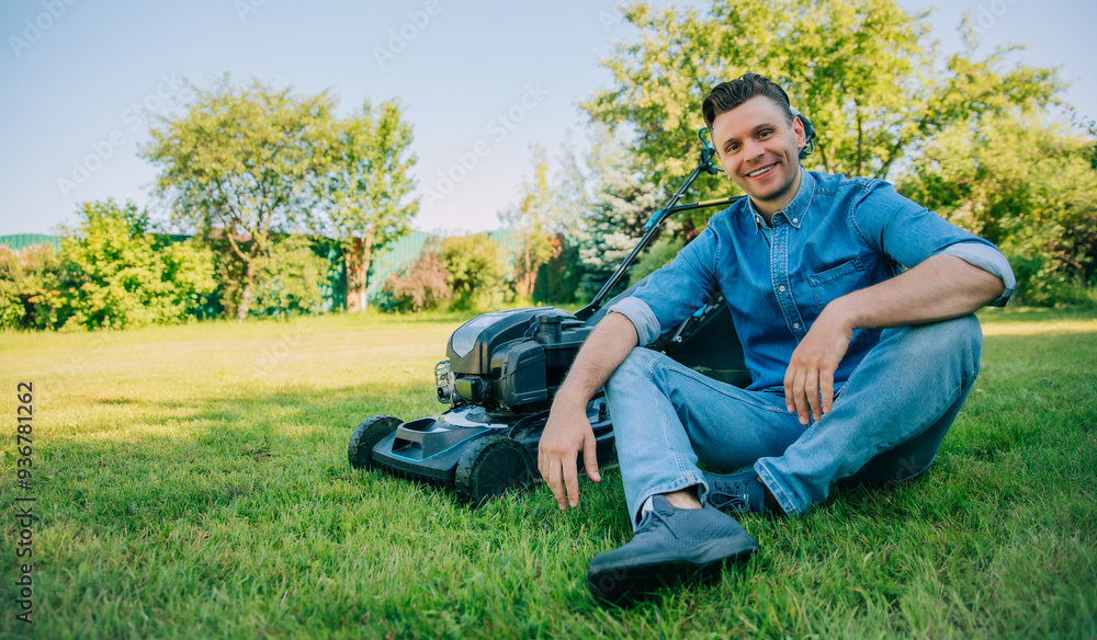 A smiling man in a denim shirt sits on a well-manicured lawn next to a lawn mower, enjoying a moment of rest after yard work. Satisfaction, outdoor relaxation, and the reward of a job well done. A smiling man in a denim shirt sits on a well-manicured lawn next to a lawn mower, enjoying a moment of rest after yard work. Satisfaction, outdoor relaxation, and the reward of a job well done.