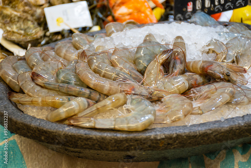 Assortment of fresh daily catch of prawns, seashells, molluscs on ice on fish market in Brittany, France, English translation: differens French names of seafood photo