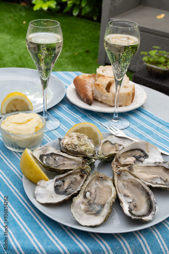 Champagne sparkling wine in glasses and oysters from Arcachon bay served on oysters farm in Gujan-Mestras, with lemon, baquette bread, butter