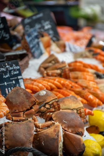 Assortment of fresh daily catch of prawns, seashells, molluscs on ice on fish market in Brittany, France, English translation: differens French names of seafood photo