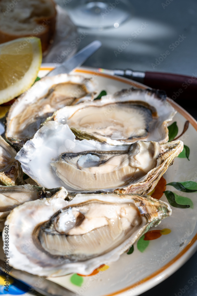 Plate with fresh live oysters with citron, bread, butter and white wine served at restaurant in oyster-farming village, Arcachon bay, Gujan-Mestras port, France Plate with fresh live oysters with citron, bread, butter and white wine served at restaurant in oyster-farming village, Arcachon bay, Gujan-Mestras port, France