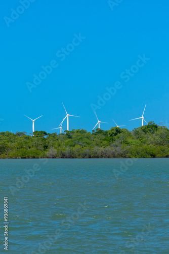 VIEW OF THE JAGUARIBE RIVER IN THE MUNICIPALITY OF FORTIM ON THE EAST COAST OF THE STATE OF CEARÁ WITH A RENEWABLE ENERGY WIND FARM UNDER THE SAND DUNES IN THE BACKGROUND.