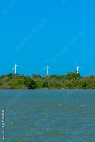 VIEW OF THE JAGUARIBE RIVER IN THE MUNICIPALITY OF FORTIM ON THE EAST COAST OF THE STATE OF CEARÁ WITH A RENEWABLE ENERGY WIND FARM UNDER THE SAND DUNES IN THE BACKGROUND.