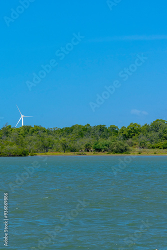 VIEW OF THE JAGUARIBE RIVER IN THE MUNICIPALITY OF FORTIM ON THE EAST COAST OF THE STATE OF CEARÁ WITH A RENEWABLE ENERGY WIND FARM UNDER THE SAND DUNES IN THE BACKGROUND. photo