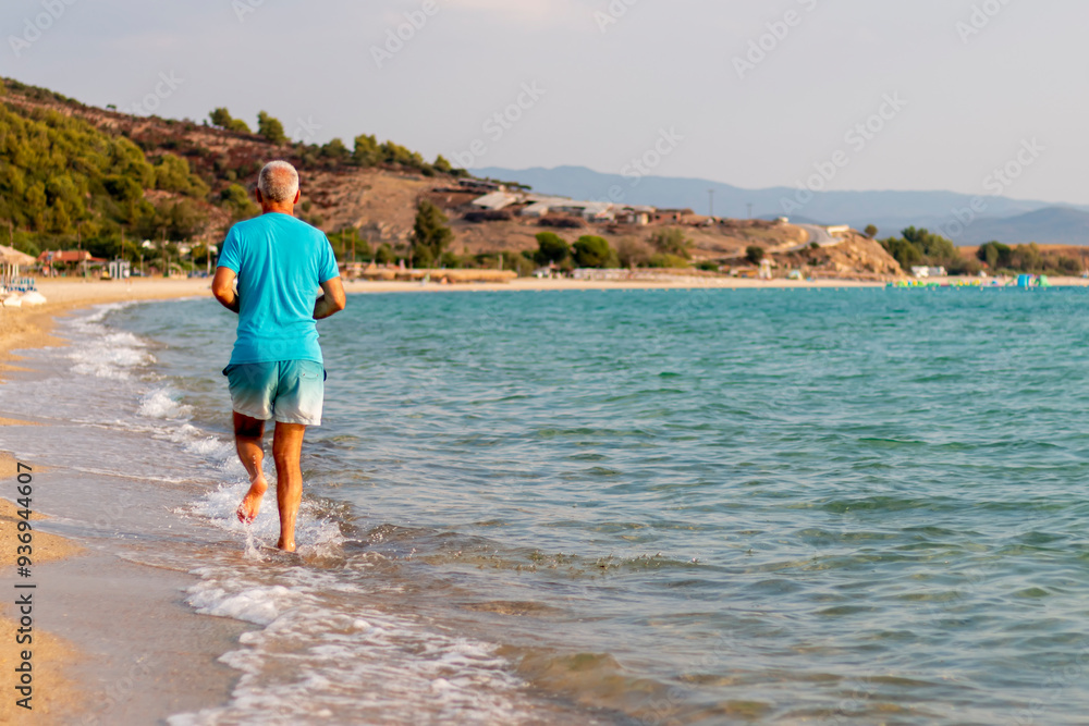 A senior man running on the beach on the day A senior man running on the beach on the day