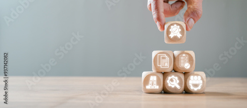 Wooden blocks with icons symbolizing ISO 9001 certification, quality management, standards, and continuous improvement in a business context.
