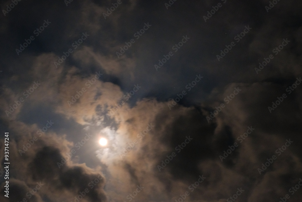 Obraz premium The atmosphere is quiet and serene on a full moon night. Textured Background of bright moonlight surrounded by clouds. Background wallpapers. Nature Photography Concept