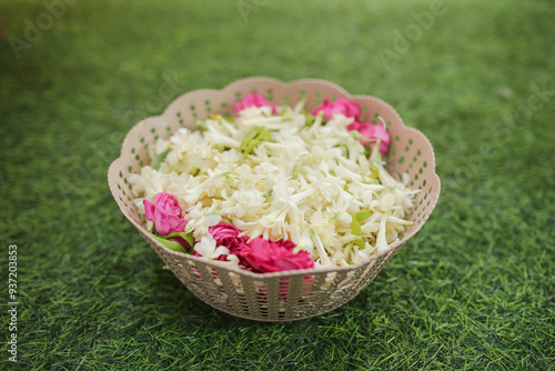 Polianthes tuberosa, and some pink rose cuttings in a bowl for a wedding event with a green grass background photo