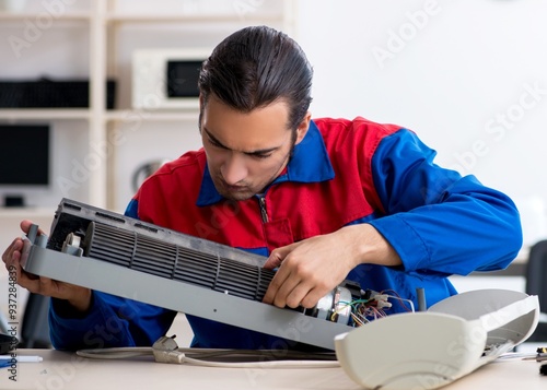 Young repairman repairing air-conditioner at warranty center photo