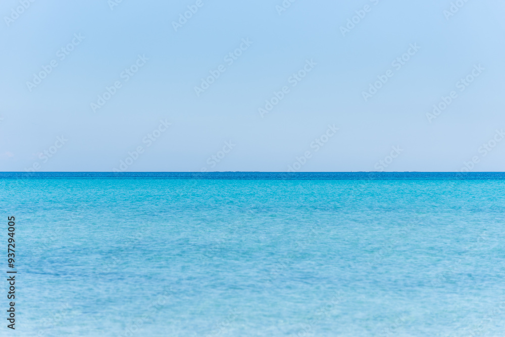 Le Saline beach landscape: turquoise sea meets a distant horizon with faint landforms, under a vast blue sky. A breathtaking view capturing the serene beauty of Sardinia's coastline. Le Saline beach landscape: turquoise sea meets a distant horizon with faint landforms, under a vast blue sky. A breathtaking view capturing the serene beauty of Sardinia's coastline.
