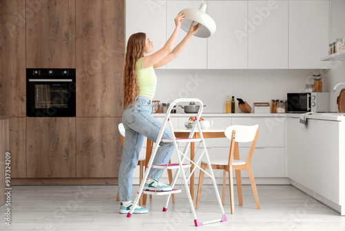 Young woman screwing light ...