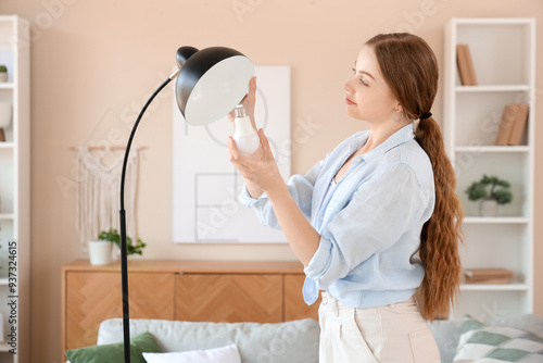 Young woman screwing light ...