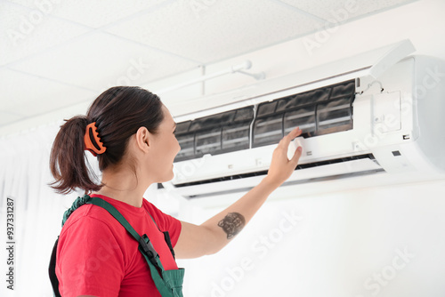 Female technician repairing air conditioner at home