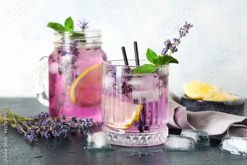 Glass and mason jar of fresh lavender lemonade with mint on dark table