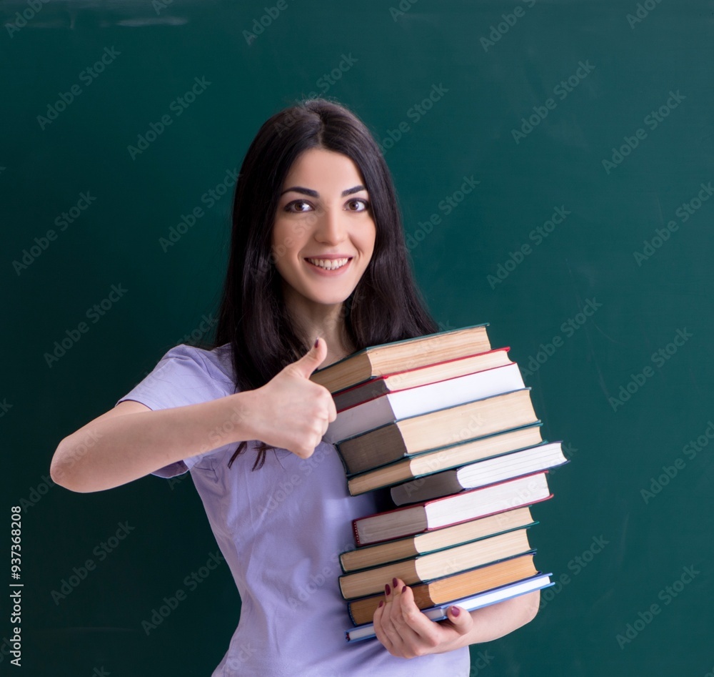 Young female teacher student in front of green board Young female teacher student in front of green board