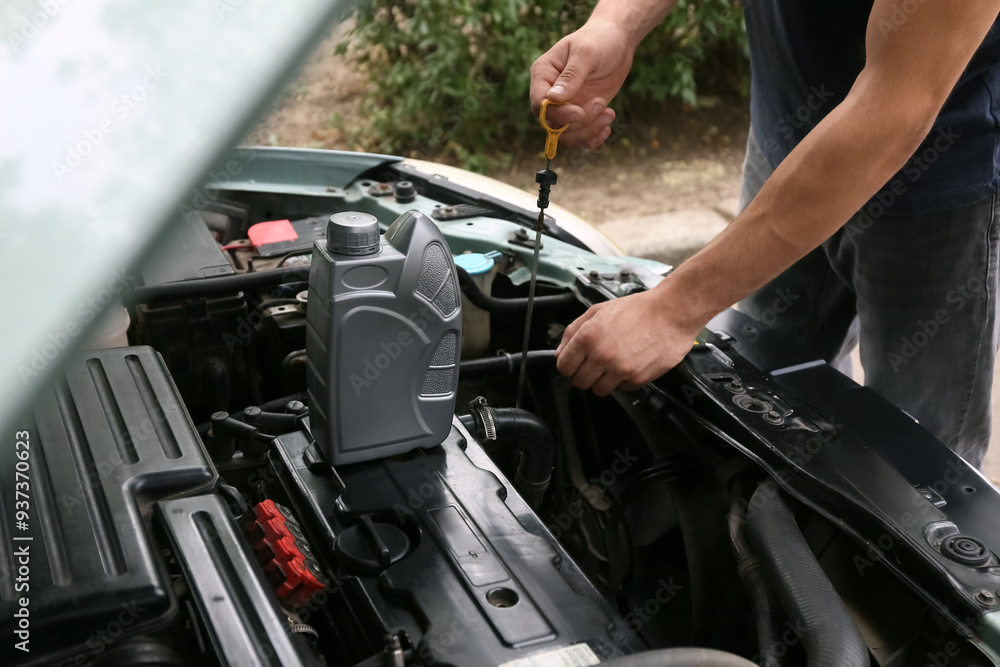 Male mechanic checking level of car oil outdoors, closeup Male mechanic checking level of car oil outdoors, closeup