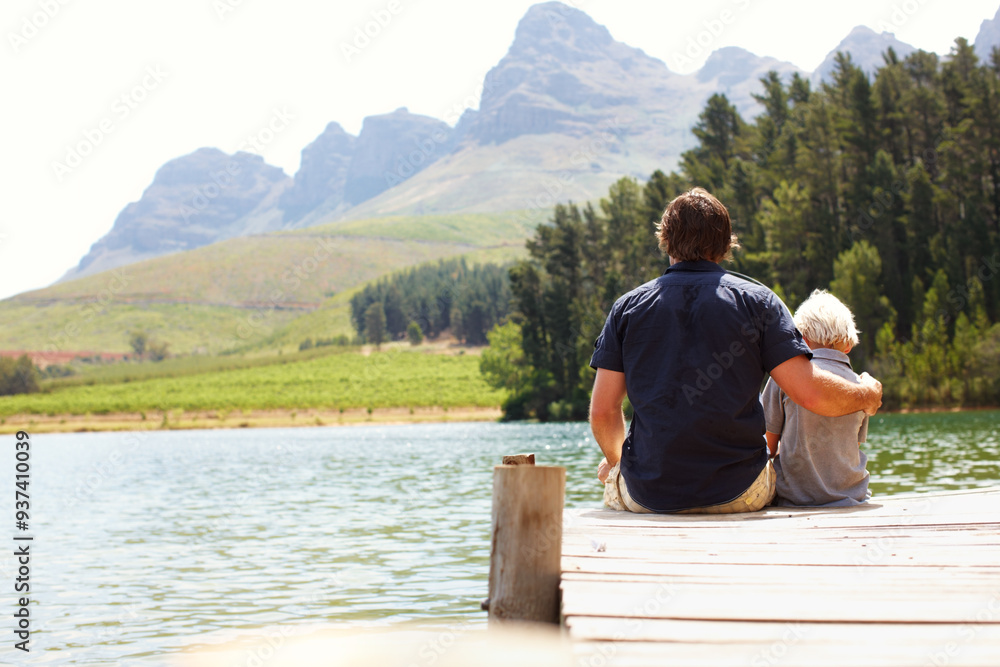 Father, boy and bonding by lake for travel, vacation and relax together in summer with back by dock. Man, child and relationship in nature for adventure, holiday and support while camping with hug Father, boy and bonding by lake for travel, vacation and relax together in summer with back by dock. Man, child and relationship in nature for adventure, holiday and support while camping with hug