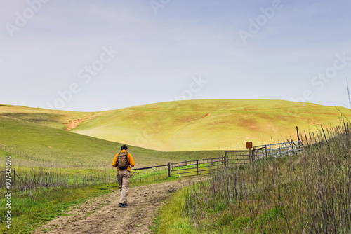 Hiker walking along a dirt path in a lush green landscape