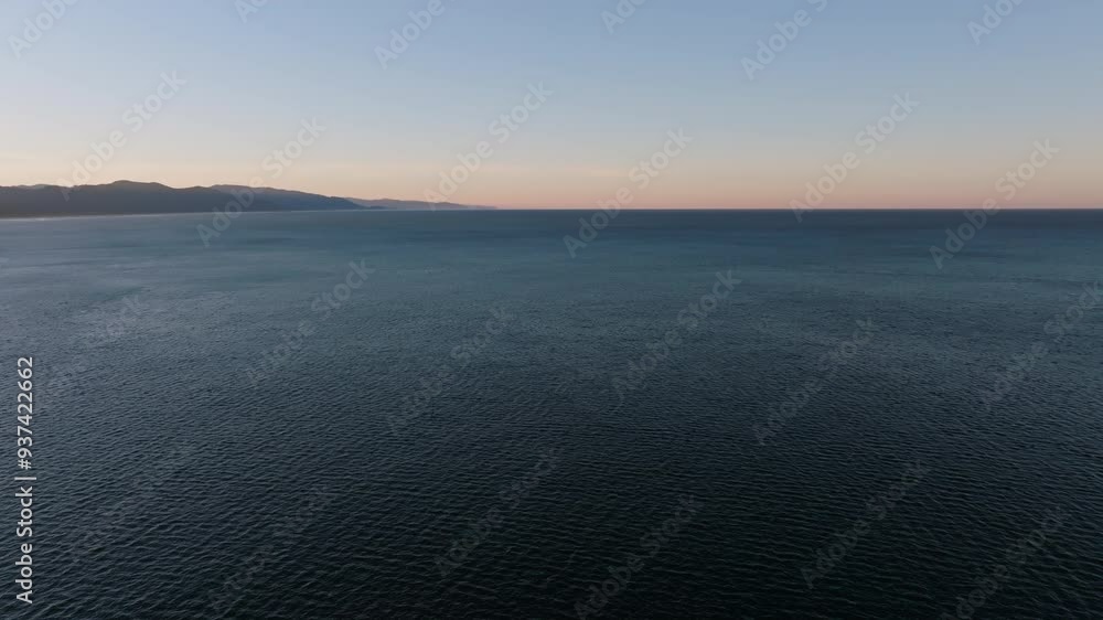 Panoramic aerial above textured ripples on open ocean water with soft sunset glow of light on horizon Panoramic aerial above textured ripples on open ocean water with soft sunset glow of light on horizon