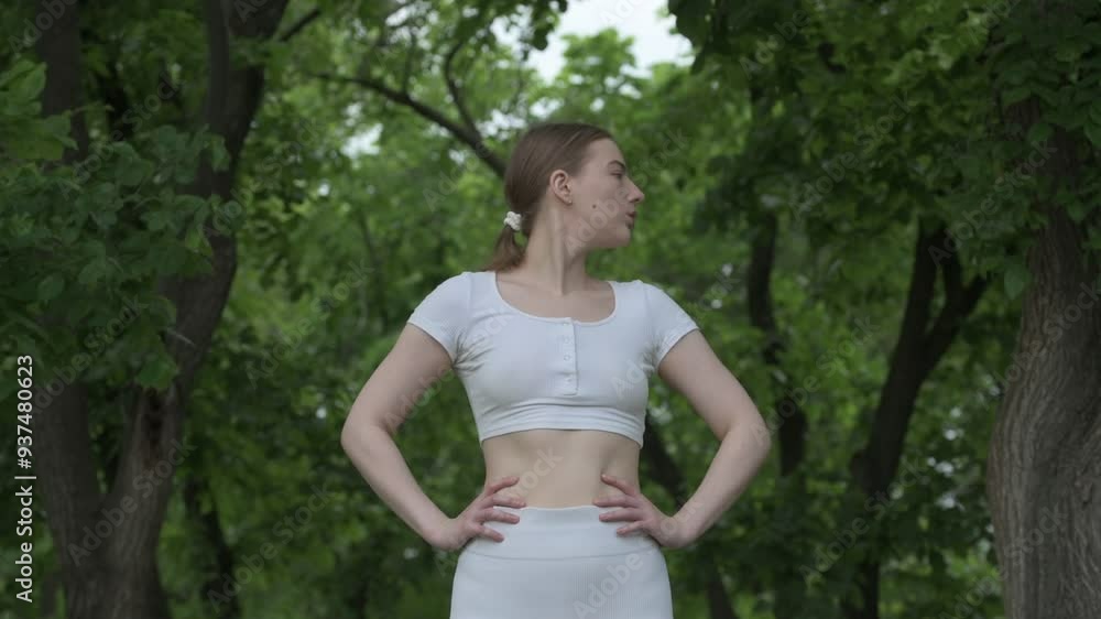 Young caucasian woman in white sportswear exercising in green forest park. Outdoor workout Young caucasian woman in white sportswear exercising in green forest park. Outdoor workout