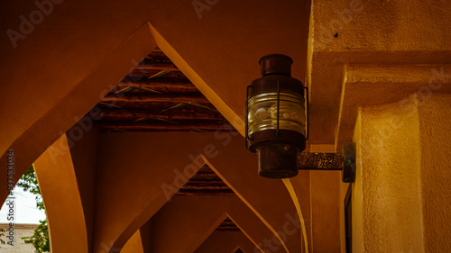 old lamp on the wall, eastern arches, street of ethnic village of Qatara photo