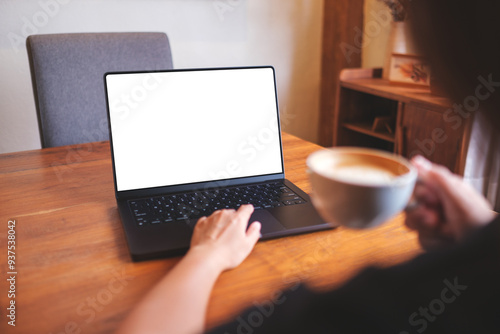 Mockup image of a woman working on laptop computer with blank white desktop screen while drinking coffee