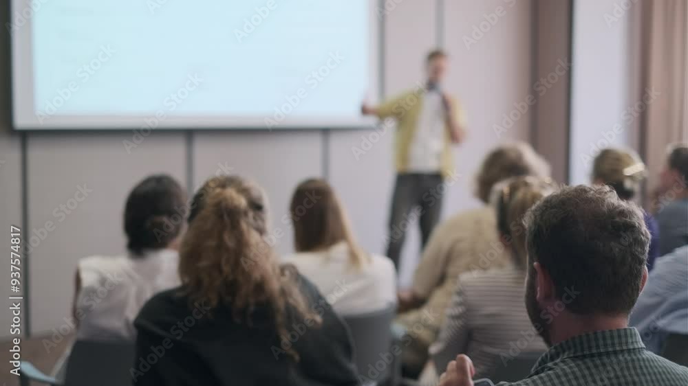 Speaker delivers a presentation to a focused audience at a business conference. The attendees are seated, listening intently, emphasizing learning and professional development. Speaker delivers a presentation to a focused audience at a business conference. The attendees are seated, listening intently, emphasizing learning and professional development.