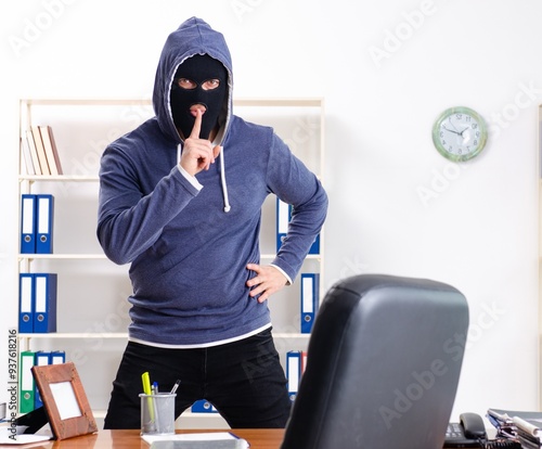 Male thief in balaclava in the office