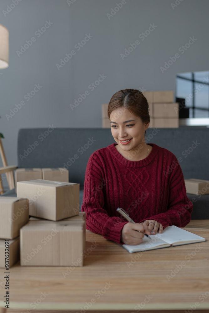 woman, online seller, using a notebook efficiently manages customer orders and delivery through the e-commerce platform woman, online seller, using a notebook efficiently manages customer orders and delivery through the e-commerce platform