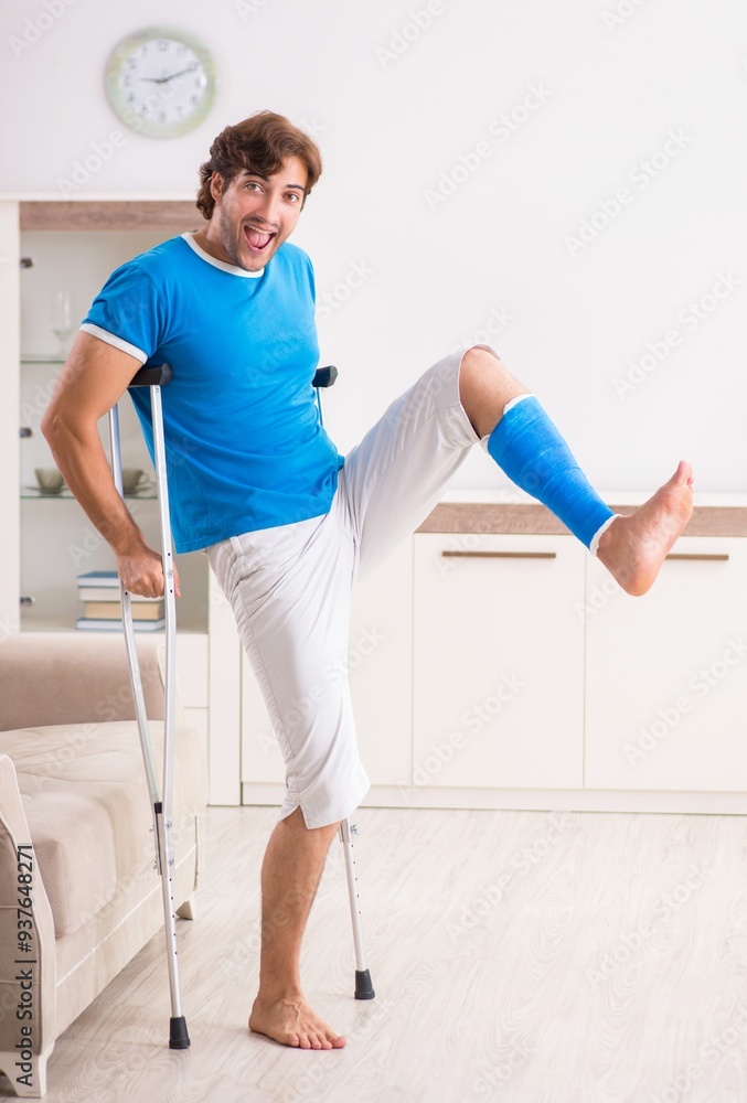 Leg injured young man with crutches at home
