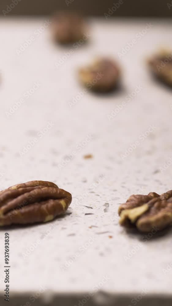 Close up of pecan nuts falling on white cutting board Close up of pecan nuts falling on white cutting board