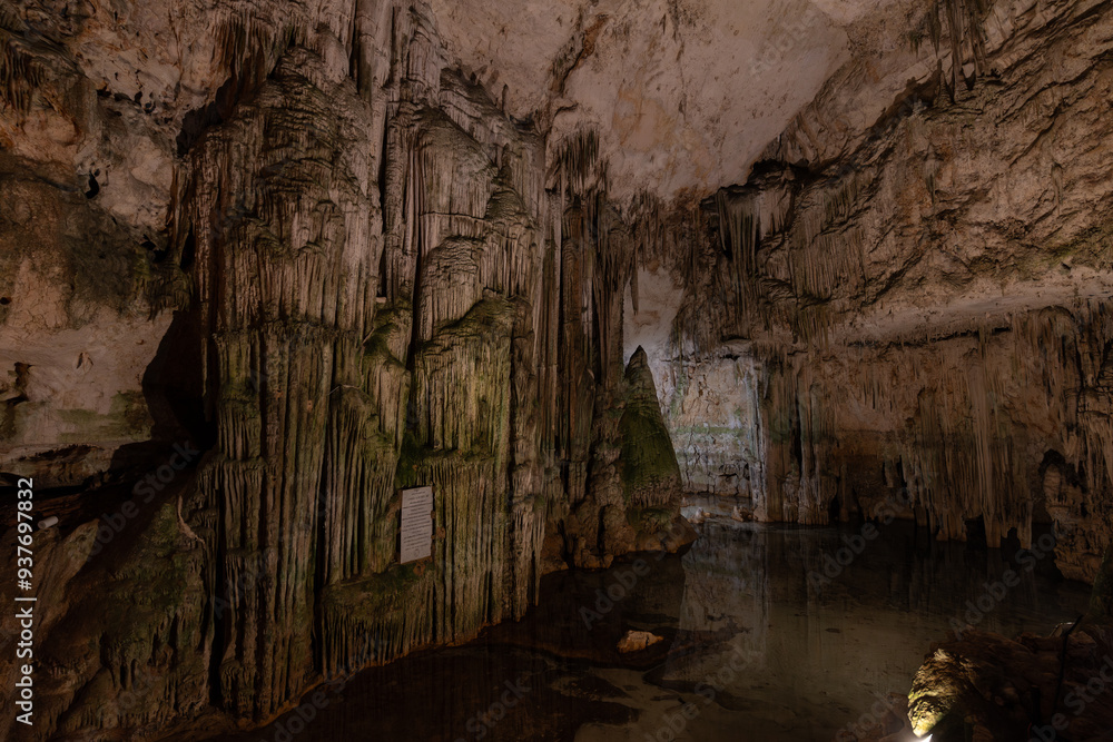 Main hall of Neptune's Grotto in Sardinia, Italy, with dramatic stalactites and stalagmites formations reflected in the water, creating a mystical atmosphere Main hall of Neptune's Grotto in Sardinia, Italy, with dramatic stalactites and stalagmites formations reflected in the water, creating a mystical atmosphere