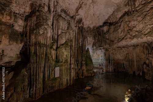 Main hall of Neptune's Grotto in Sardinia, Italy, with dramatic stalactites and stalagmites formations reflected in the water, creating a mystical atmosphere photo