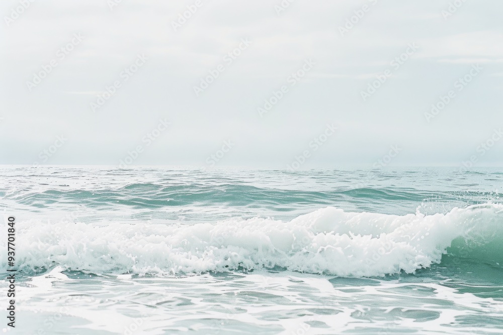 Fototapeta premium Gentle ocean waves crash and roll under a soft, overcast sky, capturing the serene and calming essence of the sea.