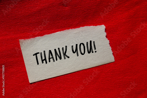 Thank you message written on ripped torn paper piece with red background. Conceptual thank you symbol. Copy space. photo