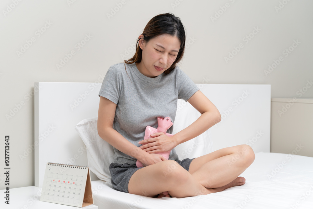 Menstruation symptom concept, Close-up woman touching her belly and feeling stomach pain from cycle period on the bed at home. Menstruation symptom concept, Close-up woman touching her belly and feeling stomach pain from cycle period on the bed at home.