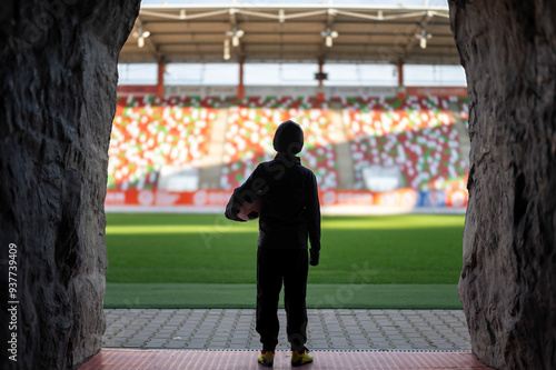 Obraz na płótnie Young the boy with the ball standing in the players' tunnel and looking at the stadium w salonie