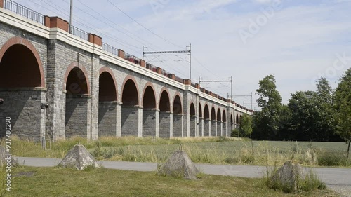 A leisurely train glides across the iconic Jezernicky viaduct in the Czech Republic. The tranquil beauty of the Czech countryside as the train slowly meanders through the lush landscape.